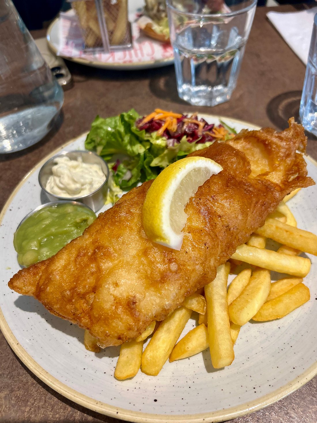 Traditional beer-battered fish and chips with mushy peas, tartar sauce and side salad